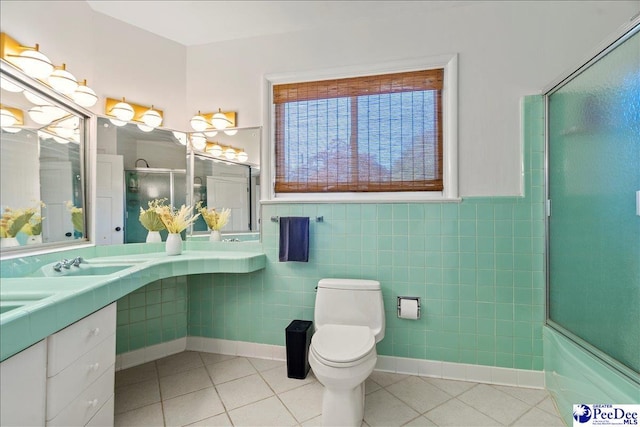 full bathroom featuring sink, enclosed tub / shower combo, tile patterned flooring, tile walls, and toilet