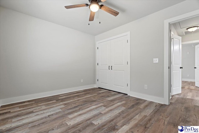 unfurnished bedroom with hardwood / wood-style flooring, ceiling fan, and a closet