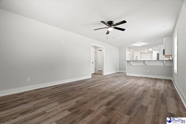 unfurnished living room with dark wood-type flooring and ceiling fan