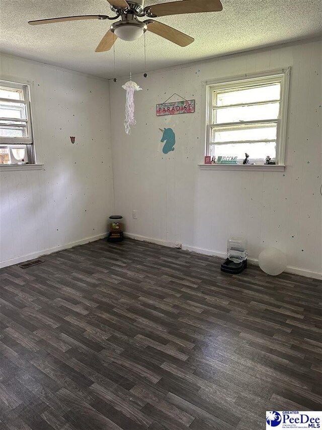 unfurnished room with plenty of natural light, dark wood-type flooring, and a textured ceiling