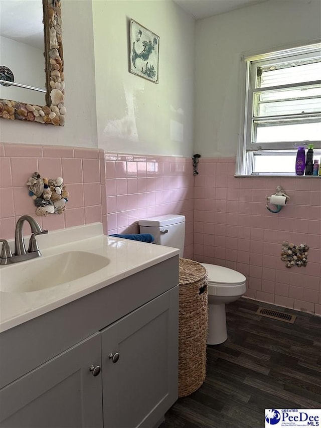 bathroom featuring vanity, toilet, hardwood / wood-style floors, and tile walls