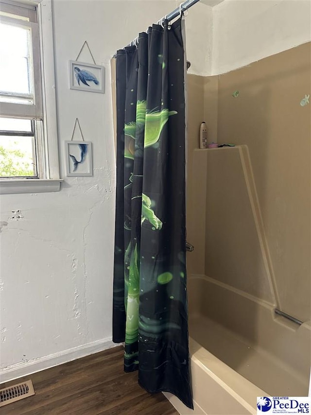 bathroom with hardwood / wood-style flooring and shower / bath combo