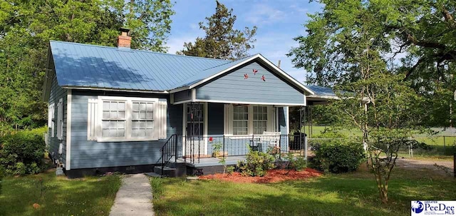 107 Patterson St, Bennettsville, SC 29512 - bungalow with a porch, a chimney, a front lawn, and metal roof