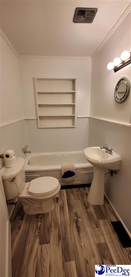 107 Patterson St, Bennettsville, SC 29512 - bathroom with toilet, a tub, wood finished floors, ornamental molding, and built in shelves