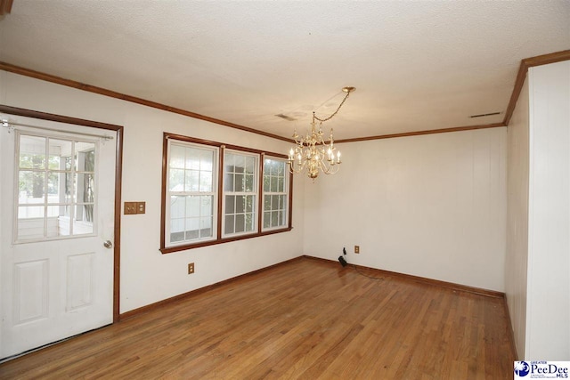 unfurnished dining area with an inviting chandelier, ornamental molding, hardwood / wood-style floors, and a textured ceiling