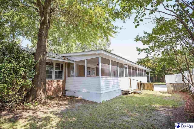 view of property exterior with a sunroom and a lawn