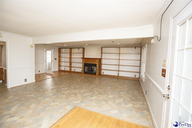 unfurnished living room with ornamental molding and a textured ceiling