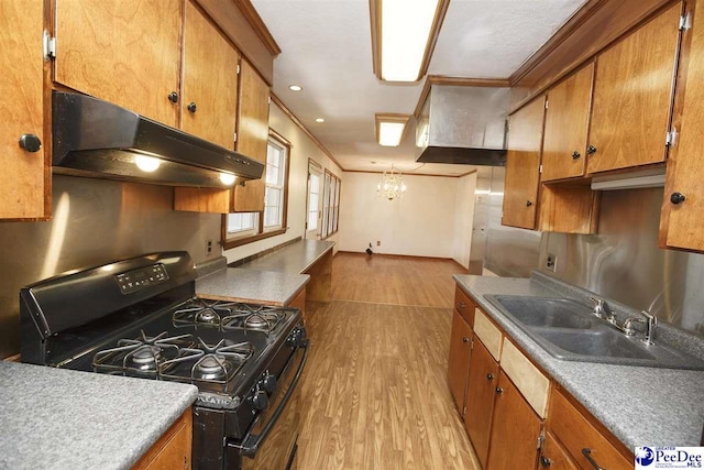 kitchen with sink, crown molding, a chandelier, light hardwood / wood-style flooring, and black gas range oven