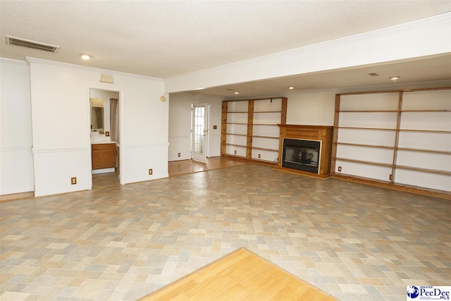 unfurnished living room featuring ornamental molding and a textured ceiling