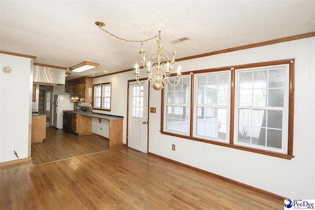 kitchen featuring dark wood-type flooring, a chandelier, ornamental molding, white fridge, and pendant lighting