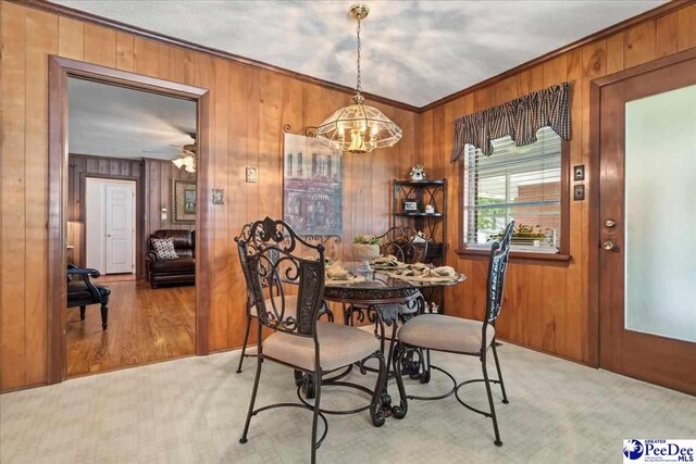 2338 W Mccown Dr, Florence, SC 29501 - dining space featuring a chandelier, crown molding, light colored carpet, and wood walls
