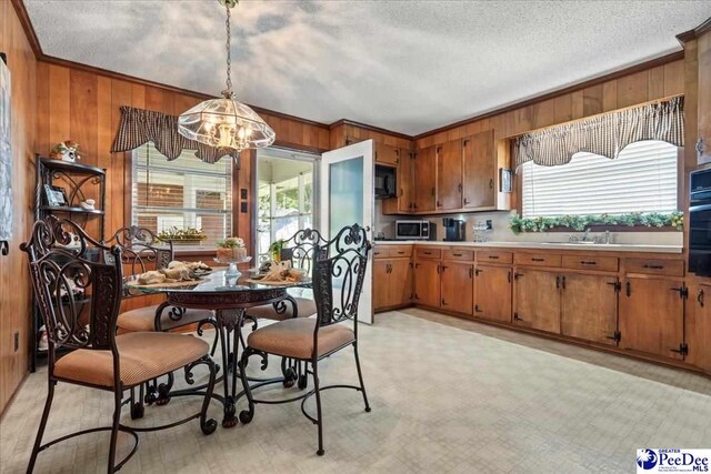 2338 W Mccown Dr, Florence, SC 29501 - dining room with a chandelier, wood walls, a textured ceiling, and ornamental molding