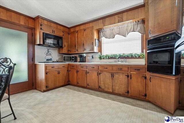 2338 W Mccown Dr, Florence, SC 29501 - kitchen with black appliances, brown cabinetry, a sink, light countertops, and wood walls