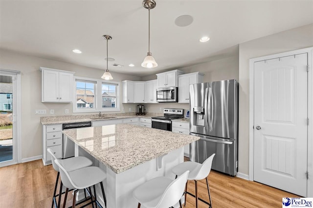 kitchen featuring hanging light fixtures, a kitchen island, appliances with stainless steel finishes, and white cabinets