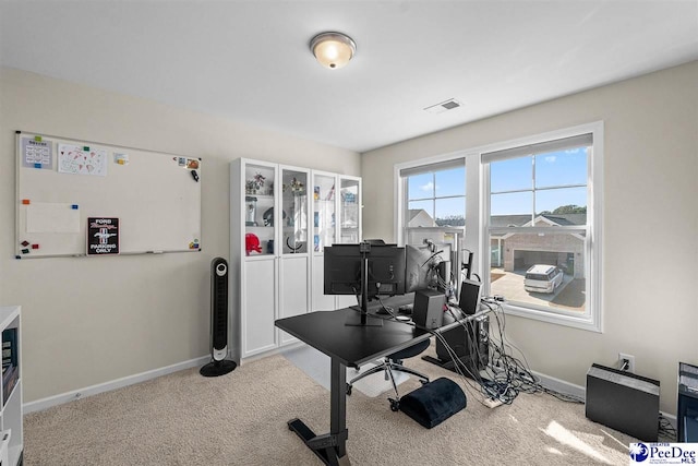 office with visible vents, baseboards, and light colored carpet