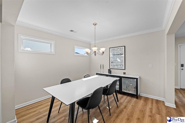 dining space with a chandelier, visible vents, baseboards, light wood-style floors, and crown molding