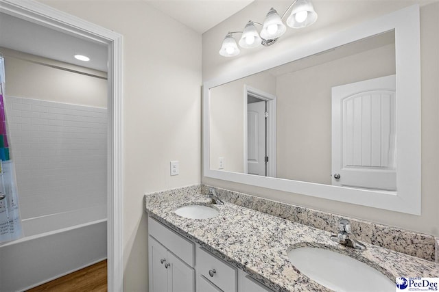 full bath with shower / bath combo with shower curtain, wood finished floors, a sink, and double vanity