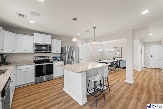 kitchen with stainless steel appliances, a center island, visible vents, and white cabinets