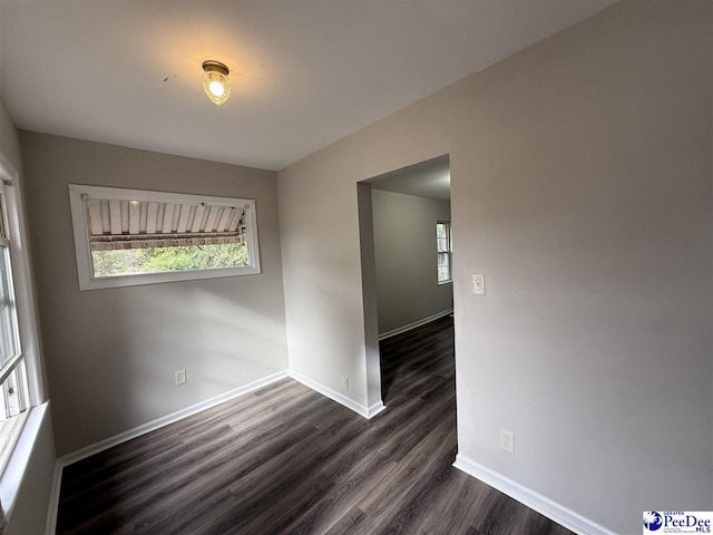 spare room featuring dark hardwood / wood-style flooring and a wealth of natural light