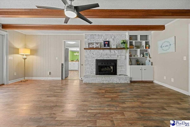 133 Peacock Row, Lamar, SC 29069 - unfurnished living room with beam ceiling, wood finished floors, a ceiling fan, baseboards, and a stone fireplace
