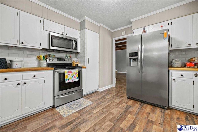 133 Peacock Row, Lamar, SC 29069 - kitchen featuring appliances with stainless steel finishes, tasteful backsplash, ornamental molding, wood finished floors, and white cabinets