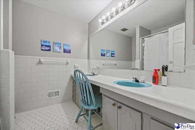 133 Peacock Row, Lamar, SC 29069 - bathroom with double vanity, a textured ceiling, wainscoting, tile patterned flooring, and tile walls