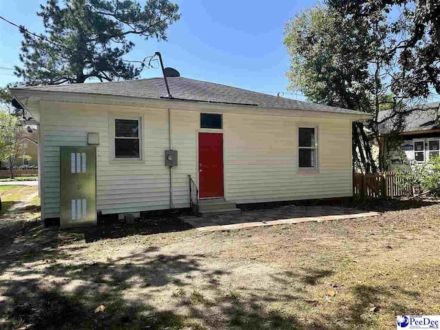 back of house featuring entry steps, fence, and roof with shingles