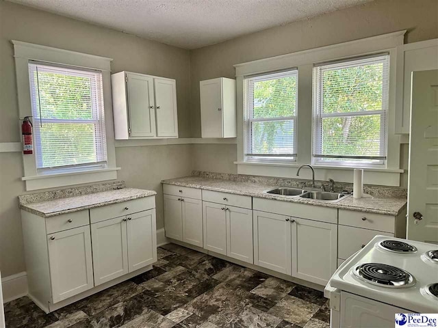 kitchen featuring electric range, a textured ceiling, white cabinets, light countertops, and a sink