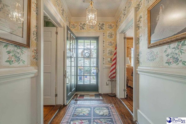 doorway featuring crown molding, dark hardwood / wood-style flooring, and an inviting chandelier