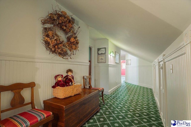 hallway with lofted ceiling and dark carpet