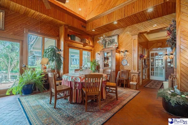 dining area featuring wood ceiling, wooden walls, and a towering ceiling