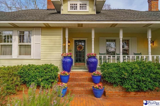 view of exterior entry featuring covered porch