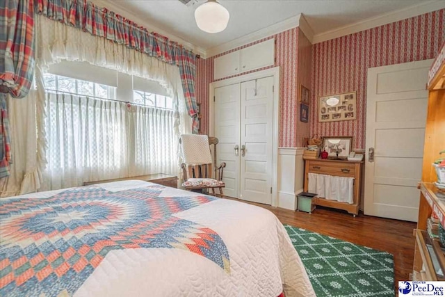 bedroom featuring dark wood-type flooring, ornamental molding, and a closet