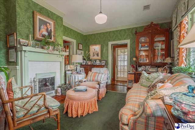 living area with ornamental molding, a brick fireplace, and dark wood-type flooring