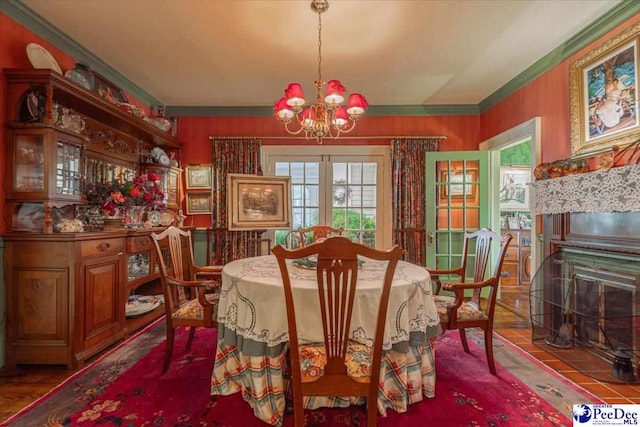 dining space featuring crown molding, a fireplace, a chandelier, and french doors