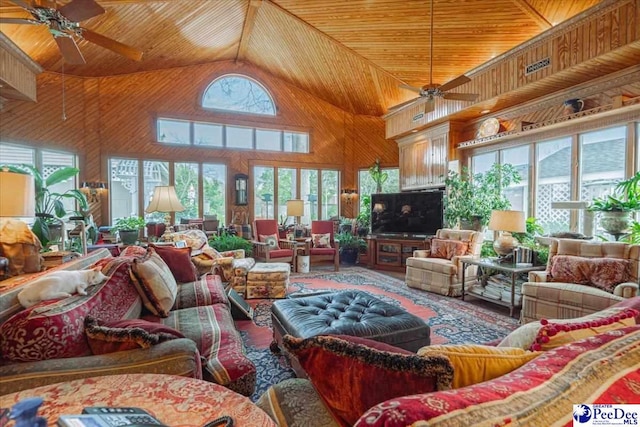 living room with high vaulted ceiling, wooden ceiling, ceiling fan, and wood walls