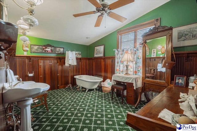 interior space featuring lofted ceiling, ceiling fan, and wood walls