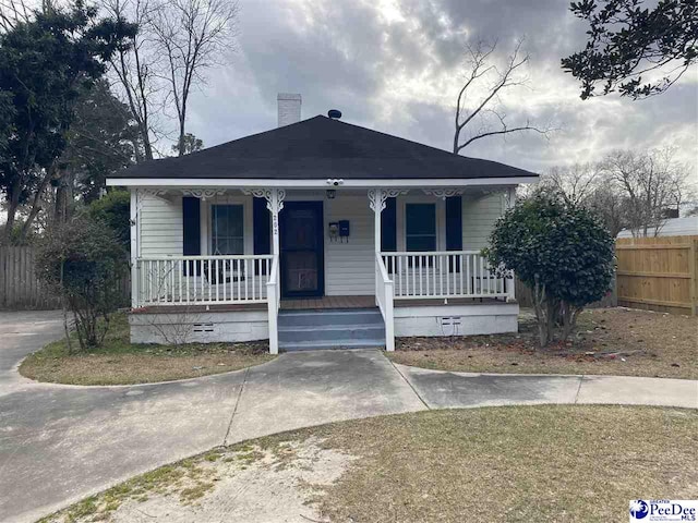 bungalow-style house featuring a porch, crawl space, a chimney, and fence