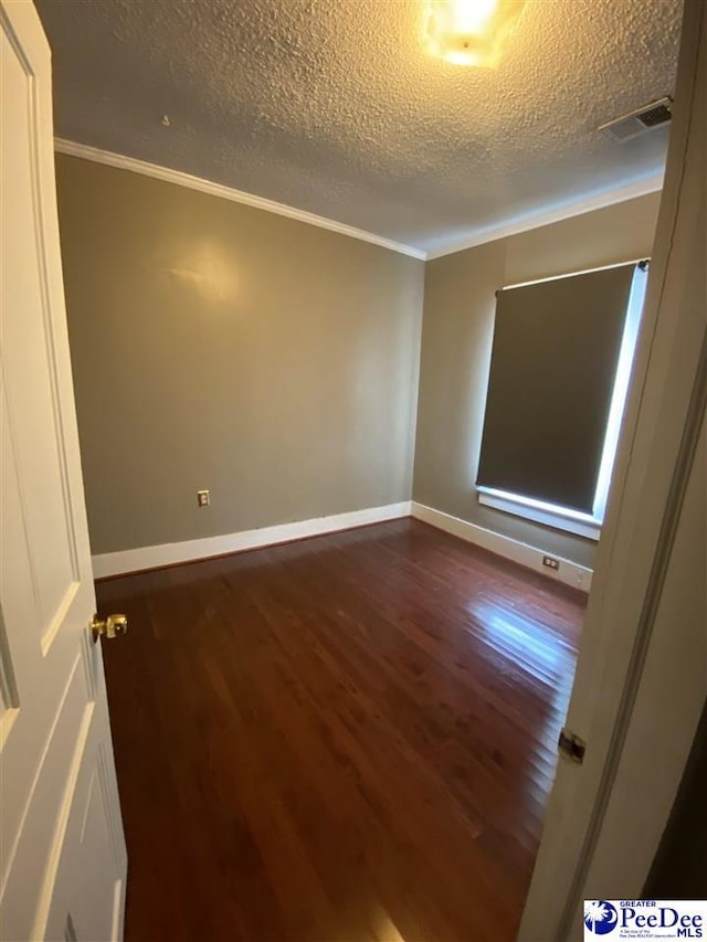 unfurnished room with a textured ceiling, visible vents, baseboards, ornamental molding, and dark wood-style floors