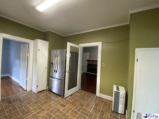 kitchen with baseboards, stainless steel refrigerator with ice dispenser, and crown molding