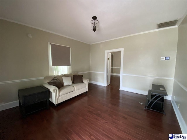 unfurnished living room featuring baseboards, visible vents, wood finished floors, and ornamental molding