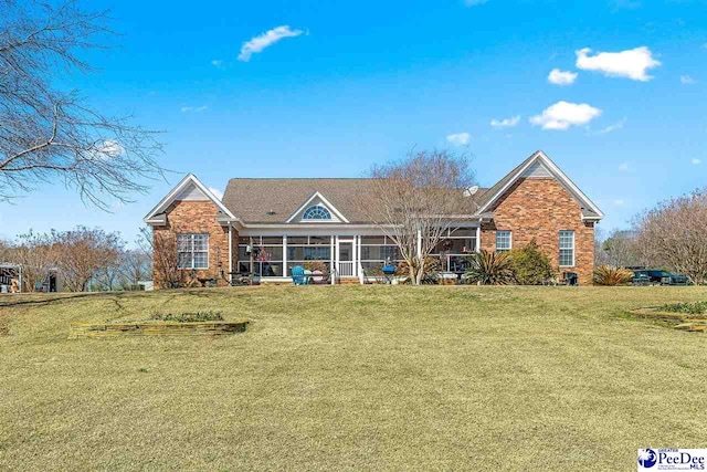 view of front of property with brick siding, a front yard, and a sunroom