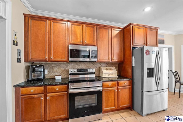 kitchen with light tile patterned floors, stainless steel appliances, decorative backsplash, ornamental molding, and dark stone countertops