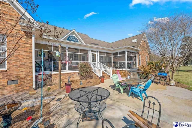 rear view of house with a patio, outdoor dining space, and a sunroom