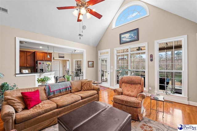 living room featuring visible vents, a ceiling fan, high vaulted ceiling, light wood-type flooring, and baseboards