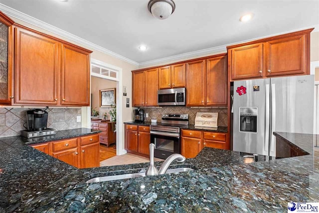 kitchen with dark stone countertops, decorative backsplash, stainless steel appliances, and a sink