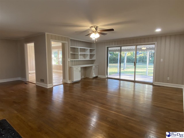 unfurnished living room featuring ornamental molding, dark hardwood / wood-style flooring, built in desk, and built in features