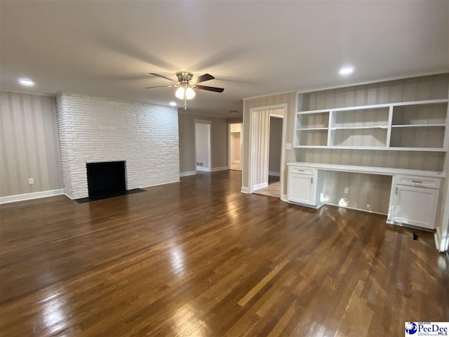 unfurnished living room with a fireplace, dark wood-type flooring, built in desk, and ceiling fan