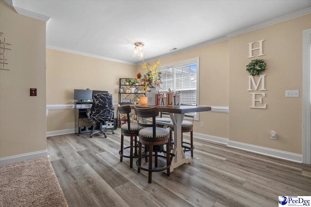 dining area featuring hardwood / wood-style flooring and ornamental molding