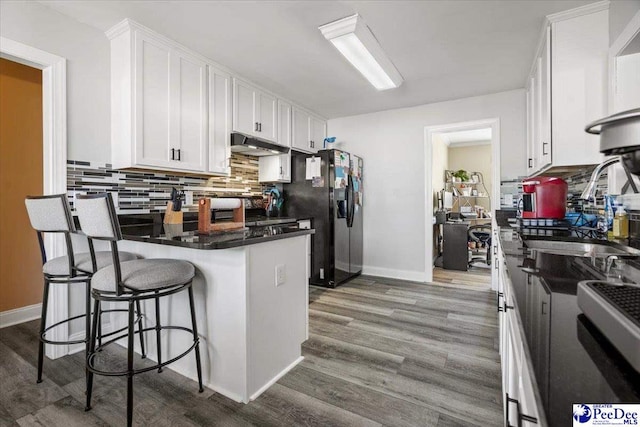 kitchen featuring white cabinetry, hardwood / wood-style floors, sink, and a breakfast bar